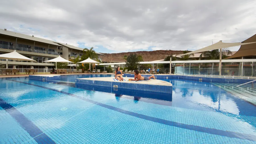 Two people relaxing by a hotel pool.